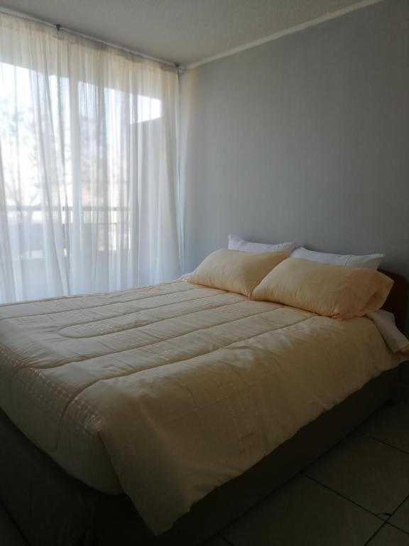 a bedroom with a large white bed with a window at Jantcar Suites in Santiago