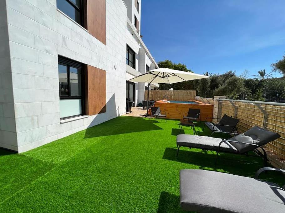 einen Hinterhof mit grünem Gras und einem Regenschirm in der Unterkunft Menahem Arber Pool 5 Bedroom in Tel Aviv