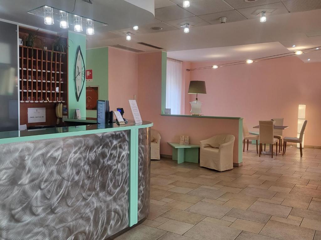 a waiting room with a counter and tables and chairs at Hotel Lux in Alessandria