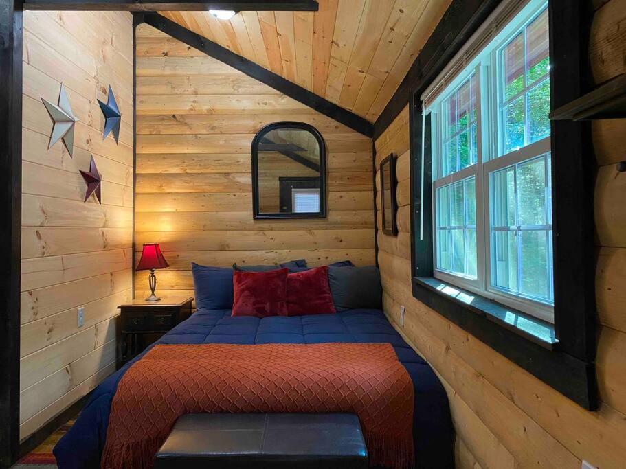 a bedroom with a blue bed in a log cabin at Cozy Log Tiny Cabin in Red River Gorge! in Campton