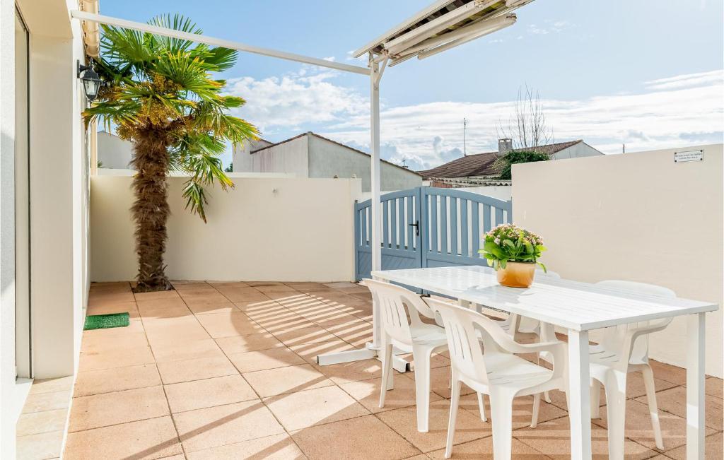 a white table and chairs on a balcony with a palm tree at Nice Home In La Faute Sur Mer With 3 Bedrooms And Wifi in La Faute-sur-Mer