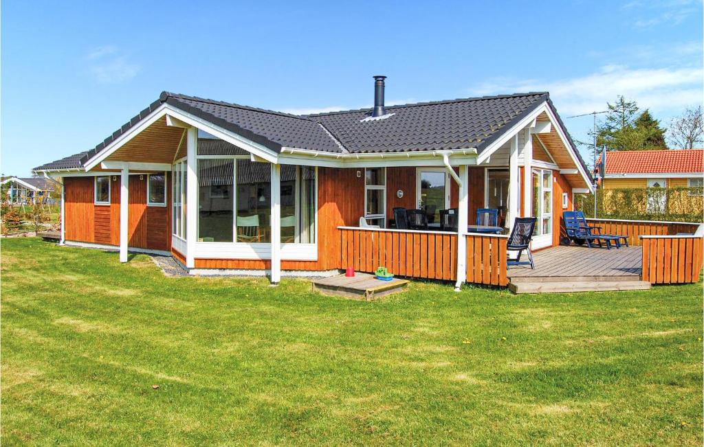 a small house with a deck and a yard at Awesome Home In Brkop With 3 Bedrooms, Sauna And Wifi in Brejning