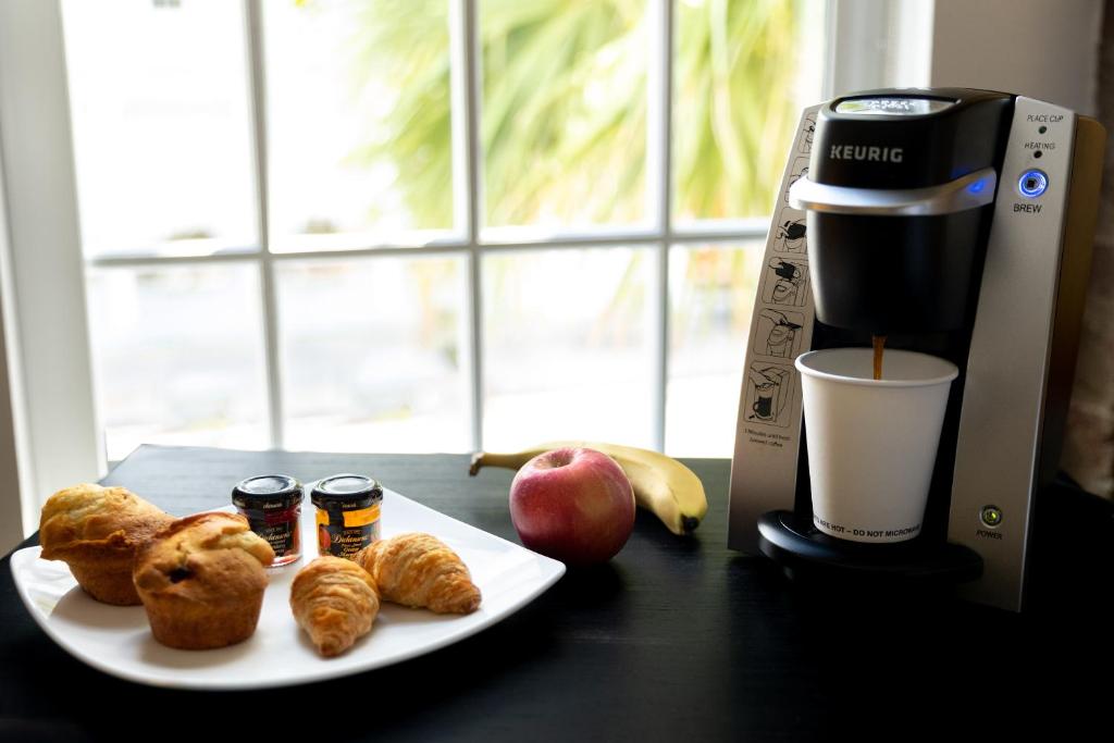 a plate of food next to a coffee maker and fruit at The Vendue, Downtown Art Hotel in Charleston