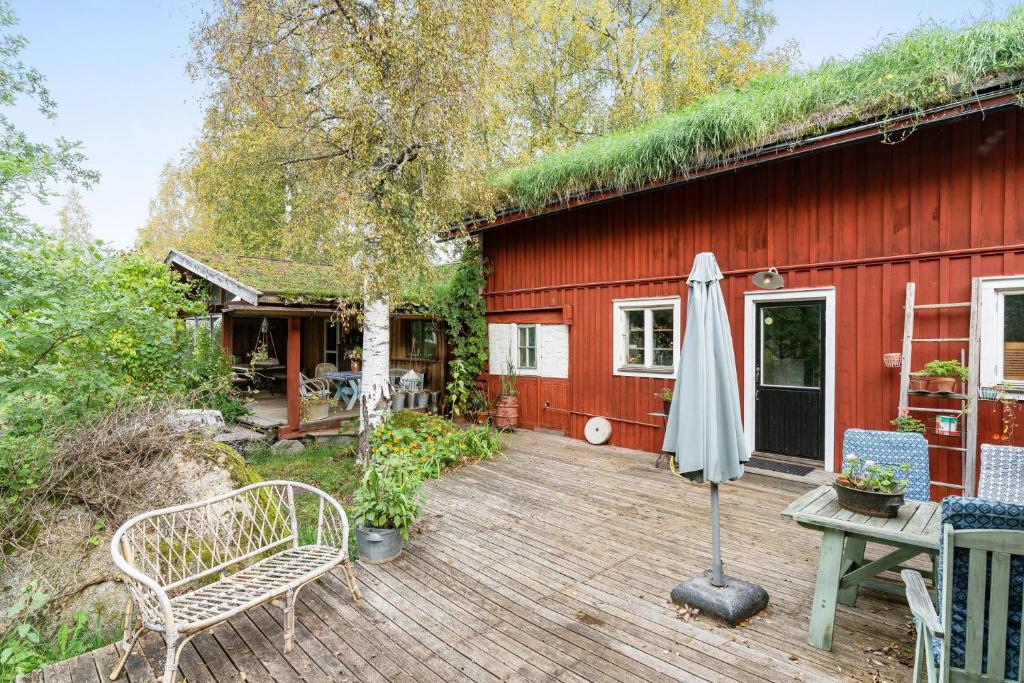 a red house with a grass roof and a wooden deck at Charming holiday home in Kungsgarden, Gastrikland in Kungsgården