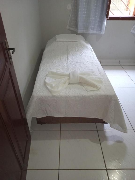 Una cama blanca con una pajarita. en Rosa do deserto en Jerônimo Monteiro