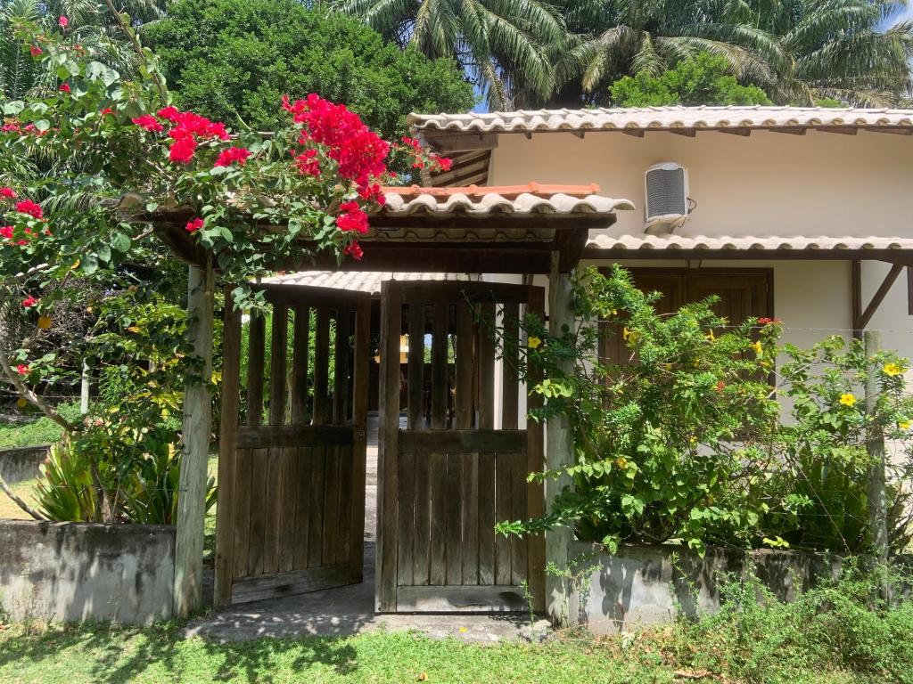 una puerta abierta a una casa con flores rojas en Casa dos Paulistas - Ilha de Boipeba, en Isla de Boipeba