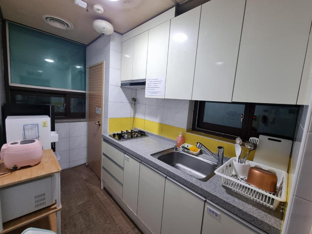 a small kitchen with white cabinets and a sink at Coem Livingtel in Goyang