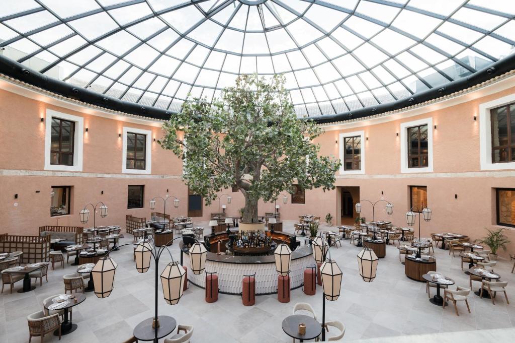 Habitación grande con mesas, sillas y techo de cristal. en Castilla Termal Brihuega en Brihuega