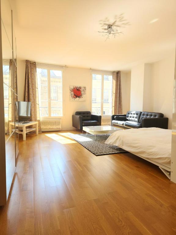 une chambre avec un lit, un canapé et une télévision dans l'établissement Chez Pierre- Between City Hall and Saint Paul, à Paris