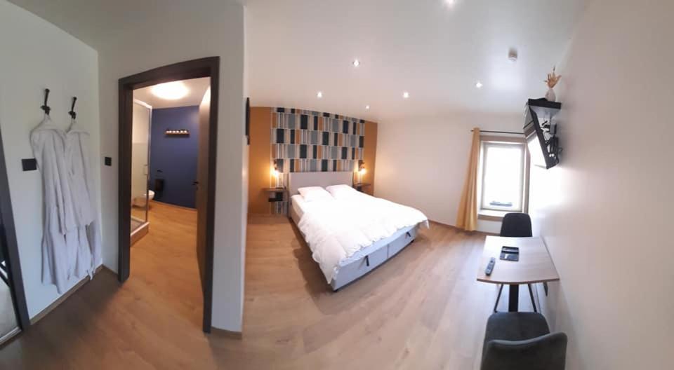 Un dormitorio con una gran cama blanca y una mesa en Les Chambres de la Fromagerie d'Ambly, en Nassogne
