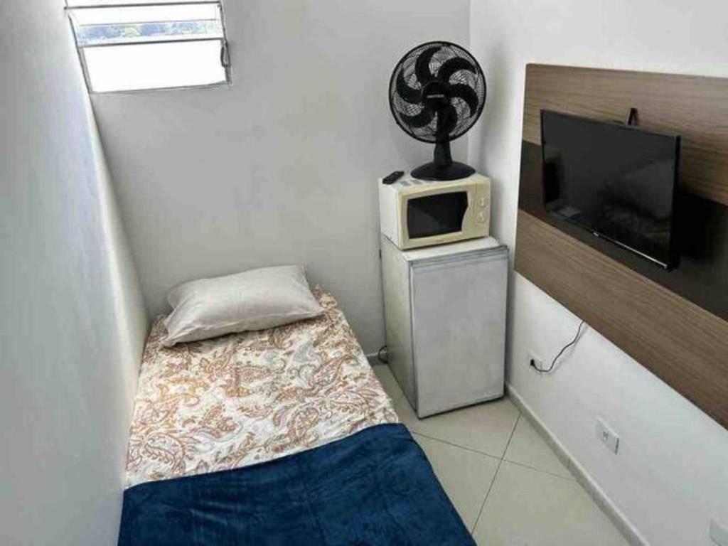 Habitación pequeña con cama y microondas. en Studio em Santana ao lado expor center norte en São Paulo