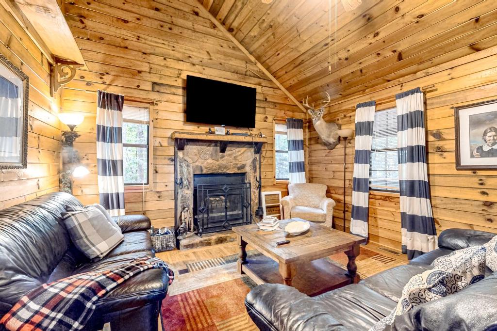 a living room with leather furniture and a fireplace at Bear Hug Lodge in Ellijay