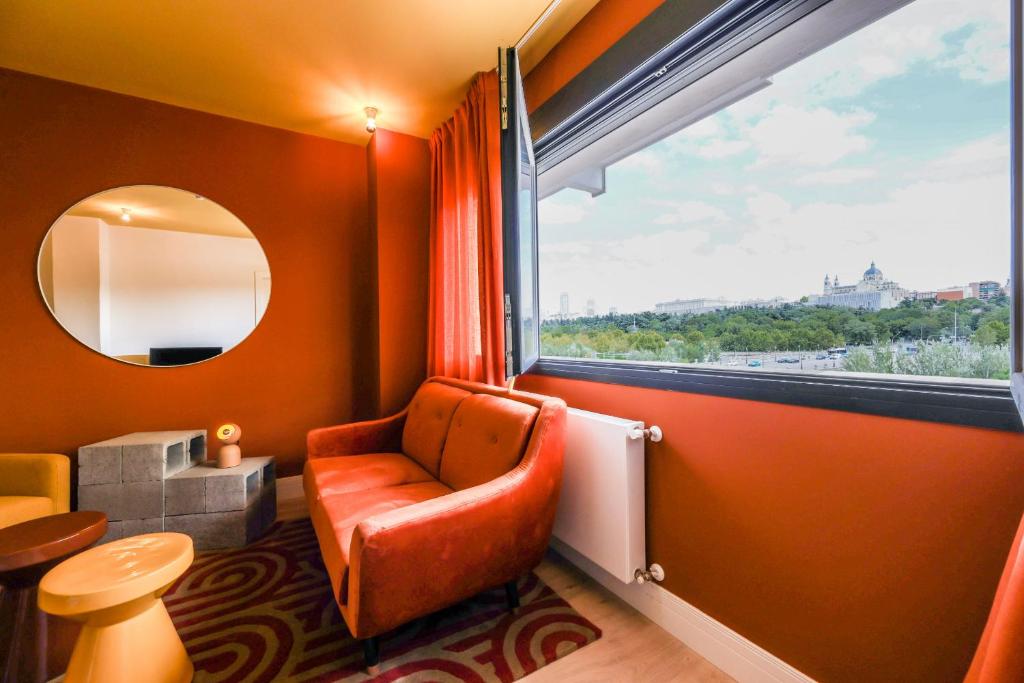Zimmer mit einem Stuhl und einem großen Fenster in der Unterkunft AmazINN Places Palacio Real in Madrid