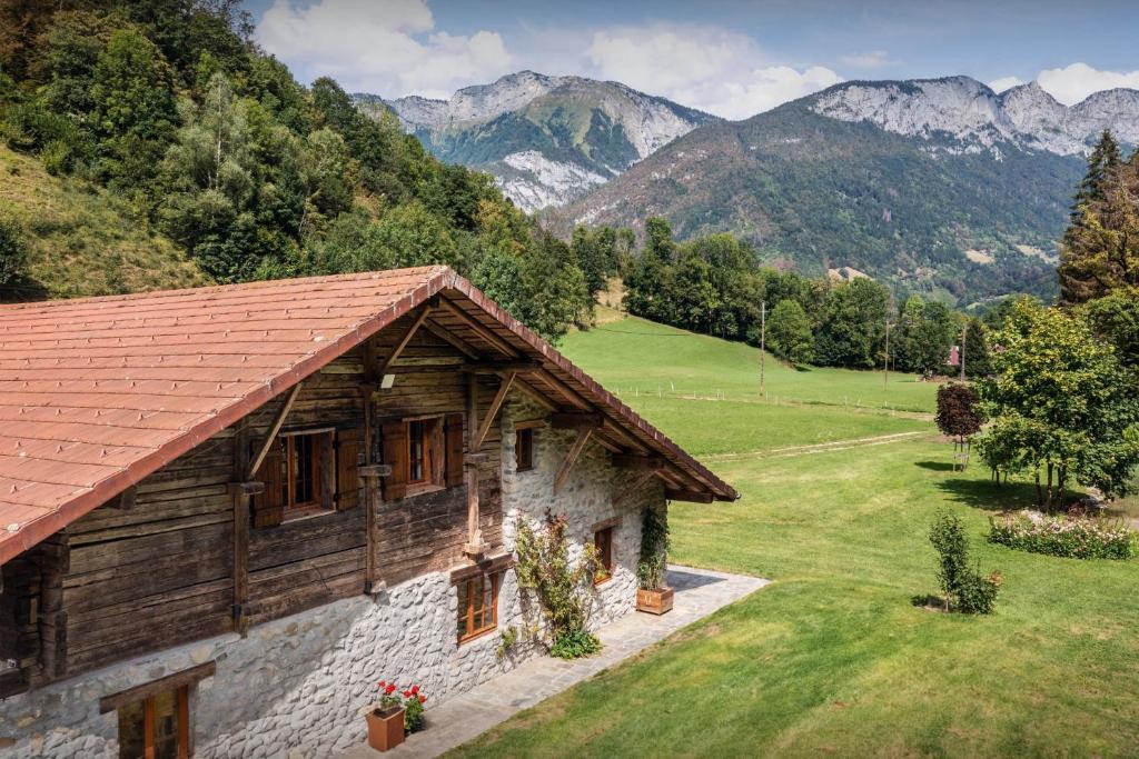 a house in a field with mountains in the background at La Ferme du Cortet - OVO Network in Thônes
