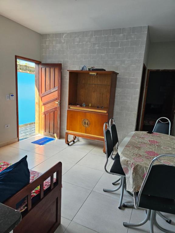 a room with a table and chairs and a wooden cabinet at Casa de praia in Mongaguá