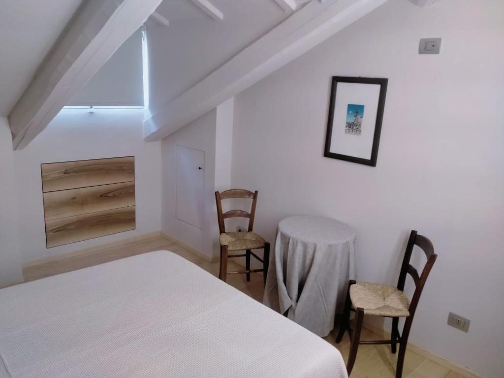 a bedroom with a white bed and two chairs at B&B San Gregorio in Cherasco