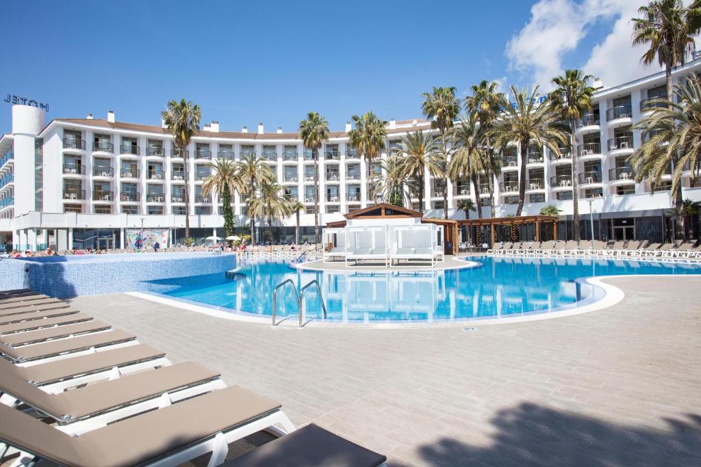 a large hotel with a swimming pool and lounge chairs at Hotel Best Cambrils in Cambrils