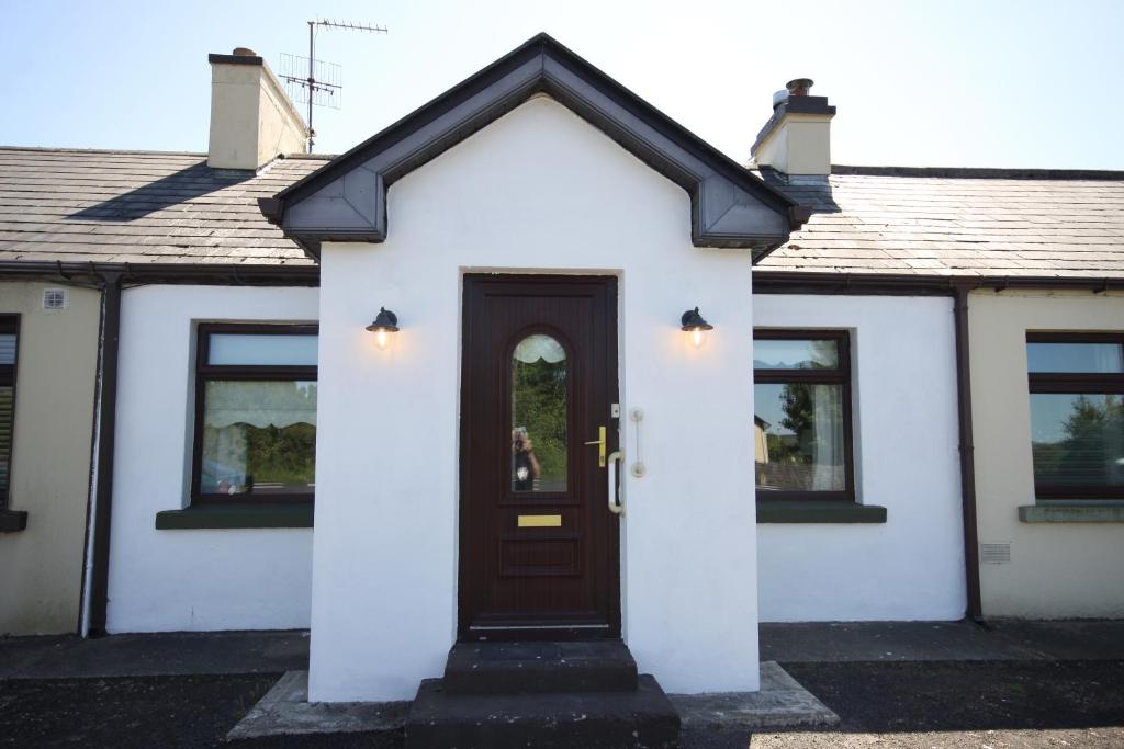 a white house with a brown door at Moy Fishermans retreat Foxford in Foxford
