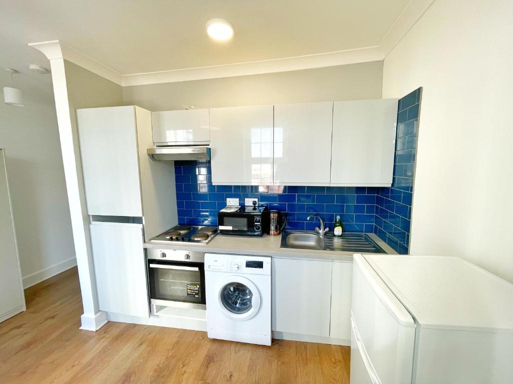 a kitchen with white cabinets and a washing machine at 1 Bedroom City Gem, Prime Location. in Woolwich