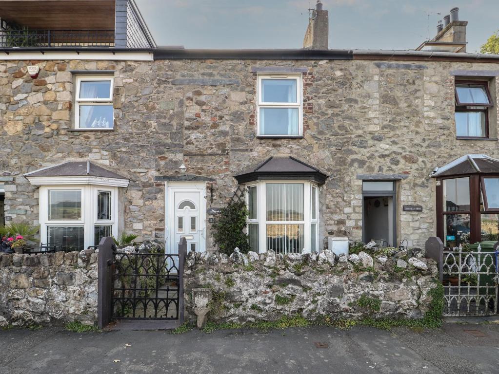 a stone house with a stone fence at 23 Beach Road in Y Felinheli