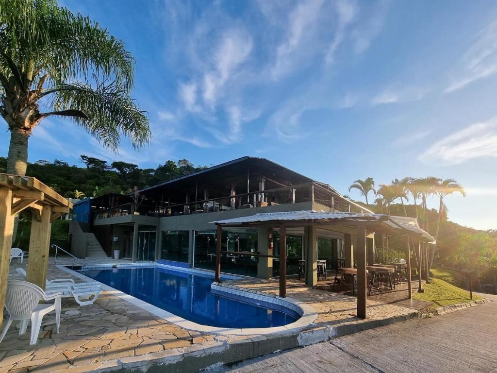 a villa with a swimming pool and a house at Hotel Caieiras in Guaratuba