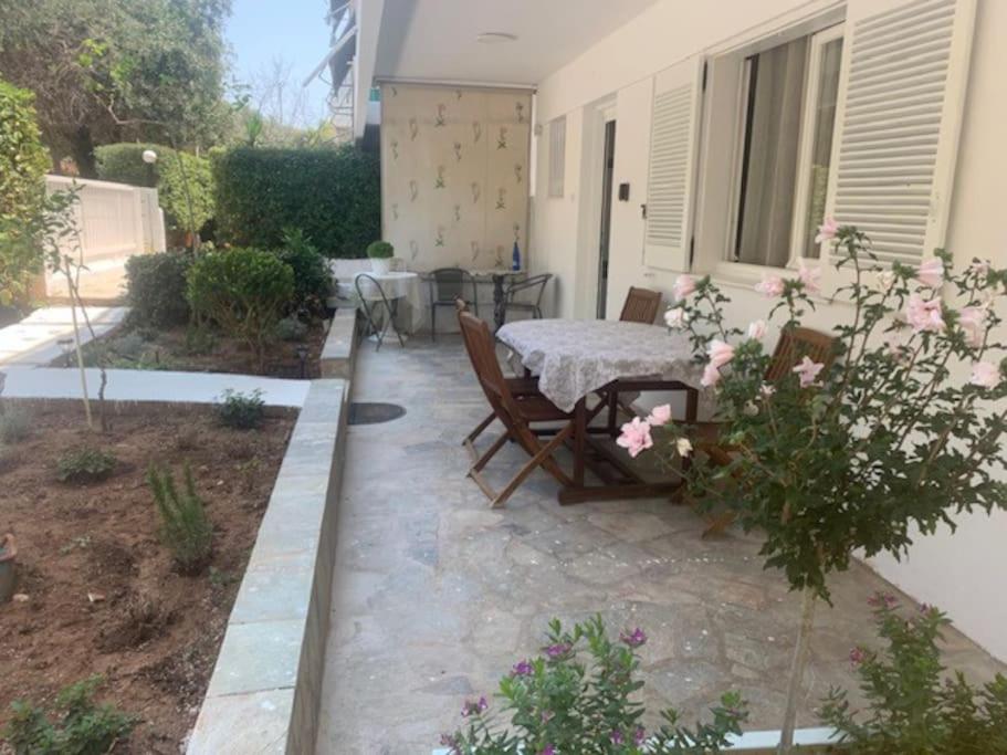 a patio with a table and chairs and flowers at Παραθαλάσσιο στούντιο με κήπο in Saronida