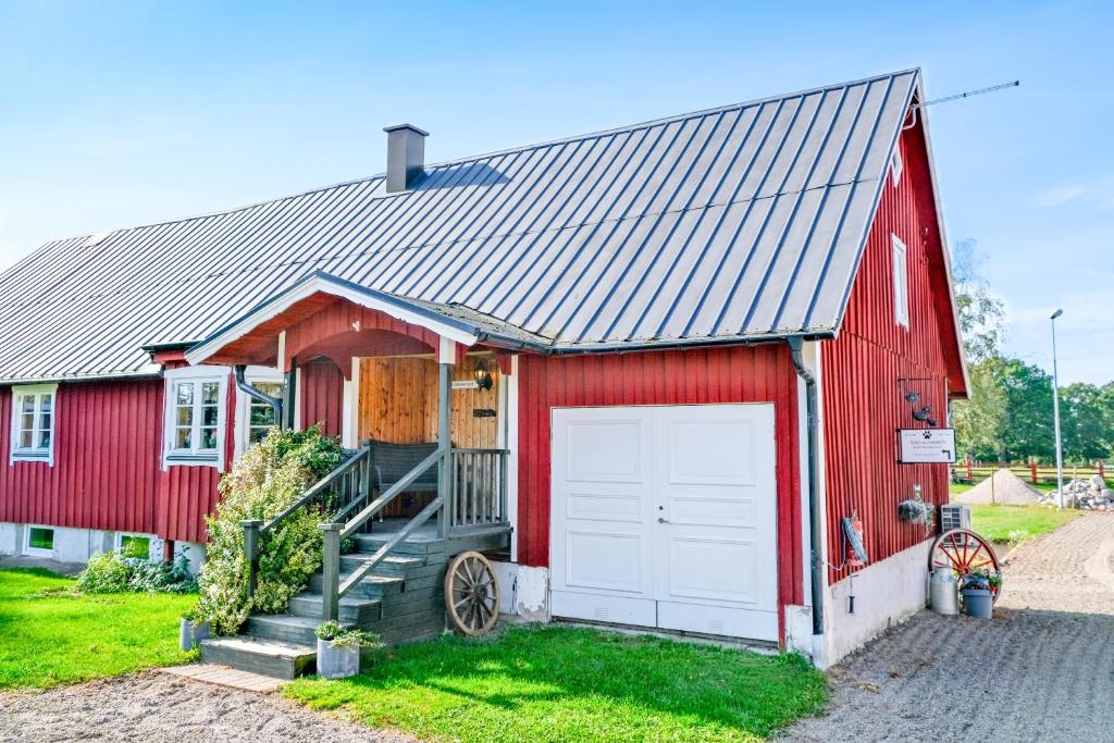 un granero rojo con un garaje blanco en Ängagården - Gårdshuset, en Våxtorp