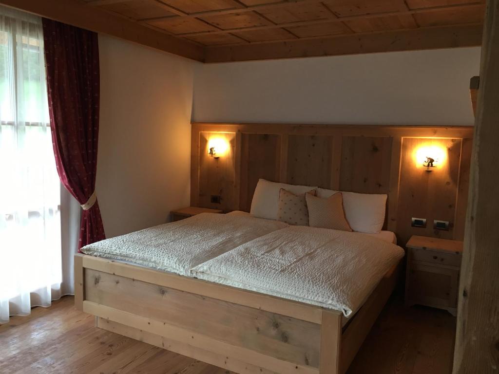 1 dormitorio con 1 cama grande y cabecero de madera en Agritur el mas, en Moena