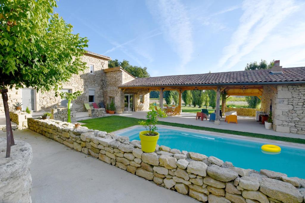 uma casa com piscina e uma parede de pedra em Le Gîte du Taureau em Sainte-Gemme
