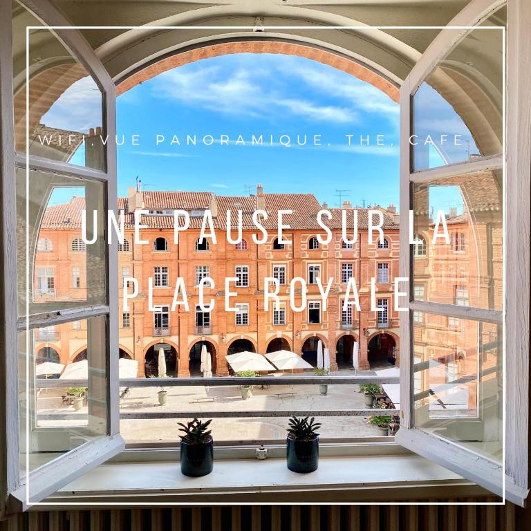 a window with a view of a building through it at une pause sur la place Royale in Montauban