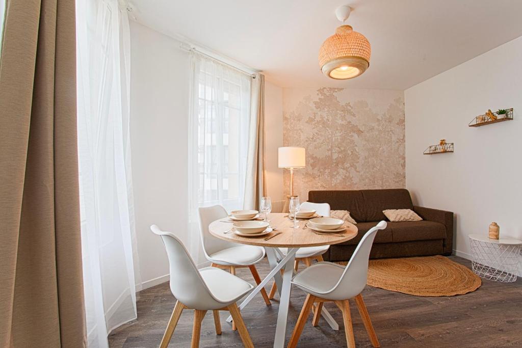 ein Wohnzimmer mit einem Tisch, Stühlen und einem Sofa in der Unterkunft Le Havre - Quartier des Docks au Calme - 4 Appartements Entièrement Rénovés - NOUVEAU in Le Havre