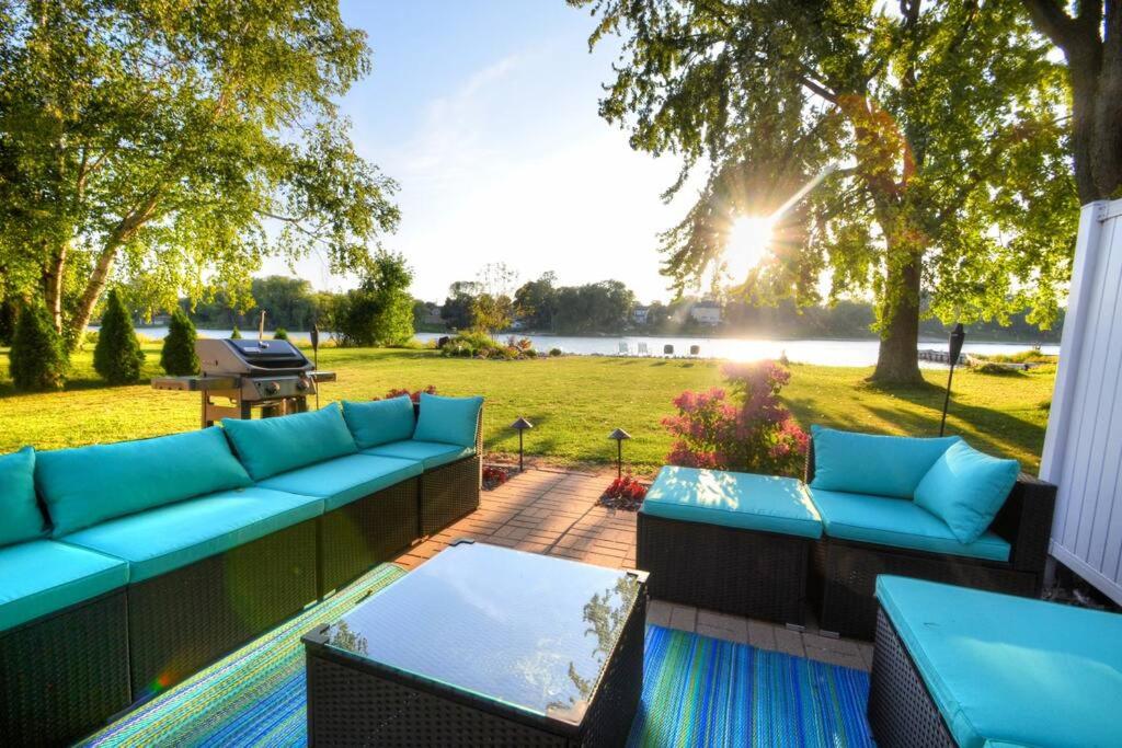 a patio with blue couches and a picnic table at Riverfront Retreat! Water front and dog friendly! in Two Rivers