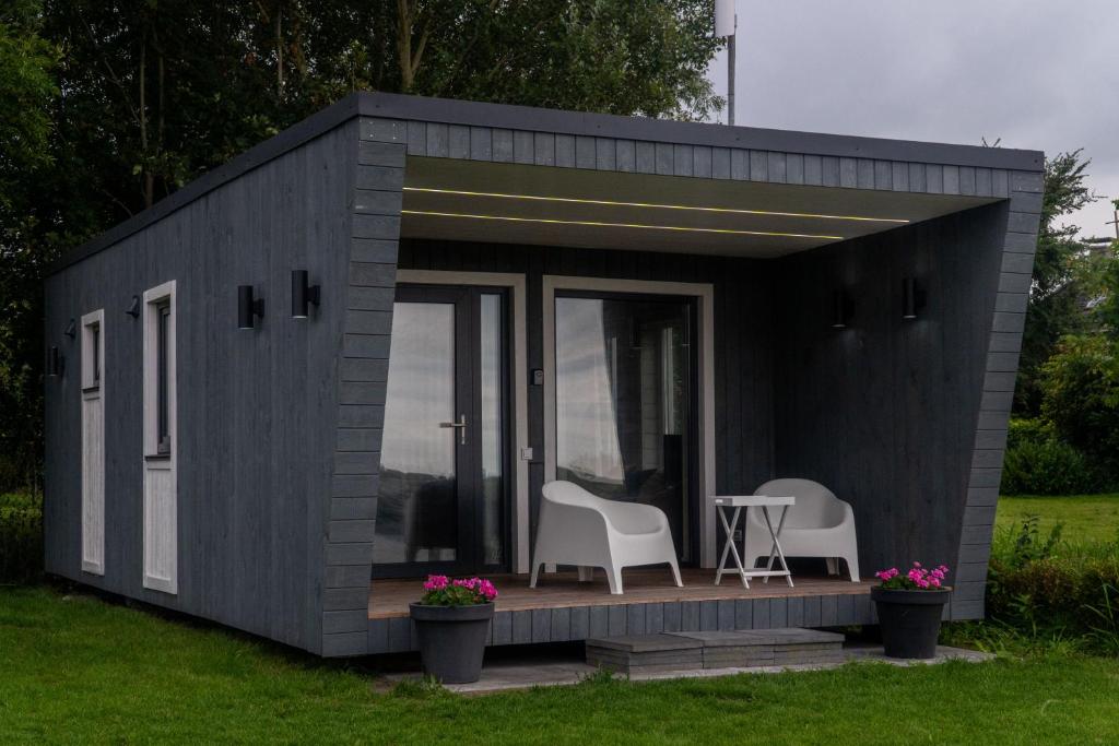 un cobertizo negro con 2 sillas y una mesa en Tiny house aan het water op de appelhof, en Wommels