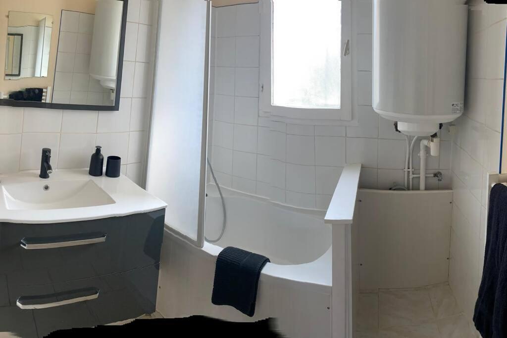 La salle de bains est pourvue d&#39;une douche, d&#39;un lavabo et d&#39;une baignoire. dans l&#39;établissement Appartement F2 hyper centre, à Lacroix-Saint-Ouen