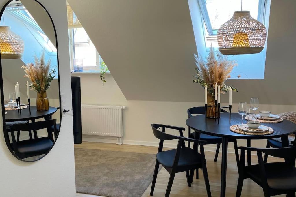 mesa de comedor con sillas y espejo en Ophold i hjertet af Odense!, en Odense