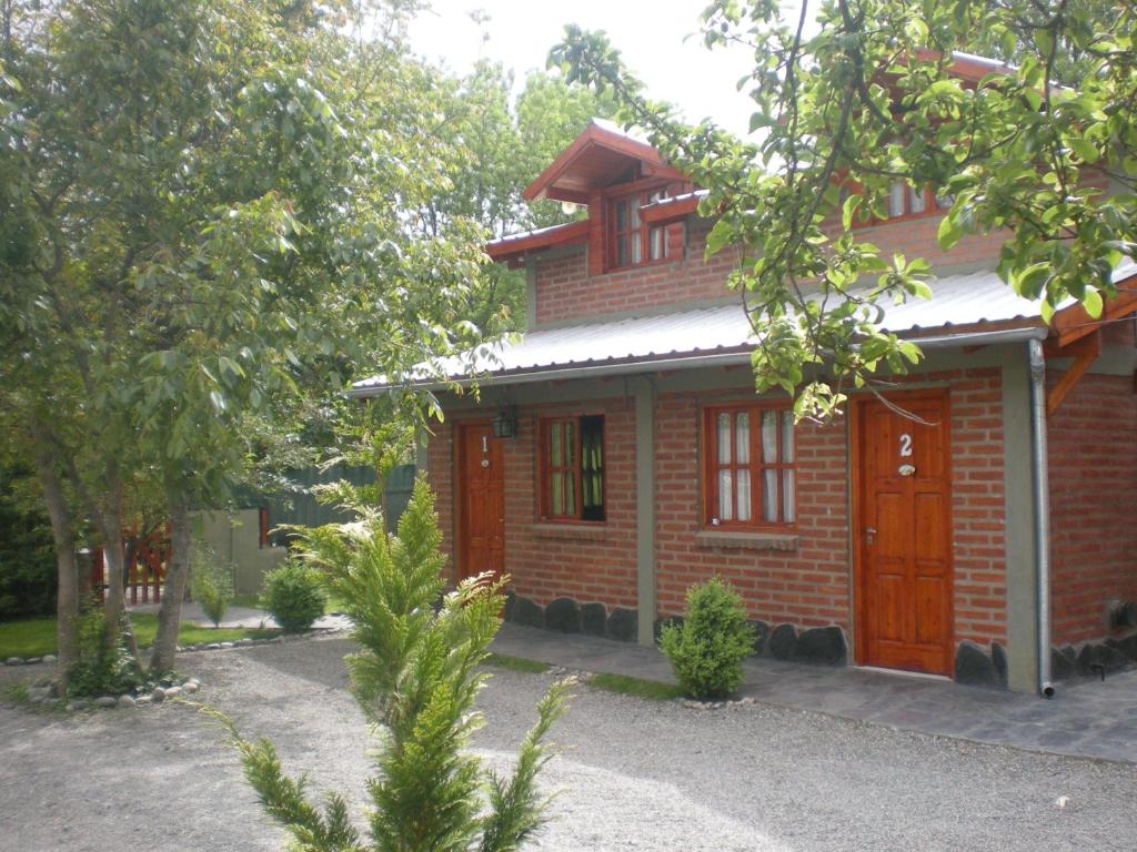ein rotes Backsteinhaus mit einer roten Tür in der Unterkunft Cabañas Tunquelen in El Bolsón