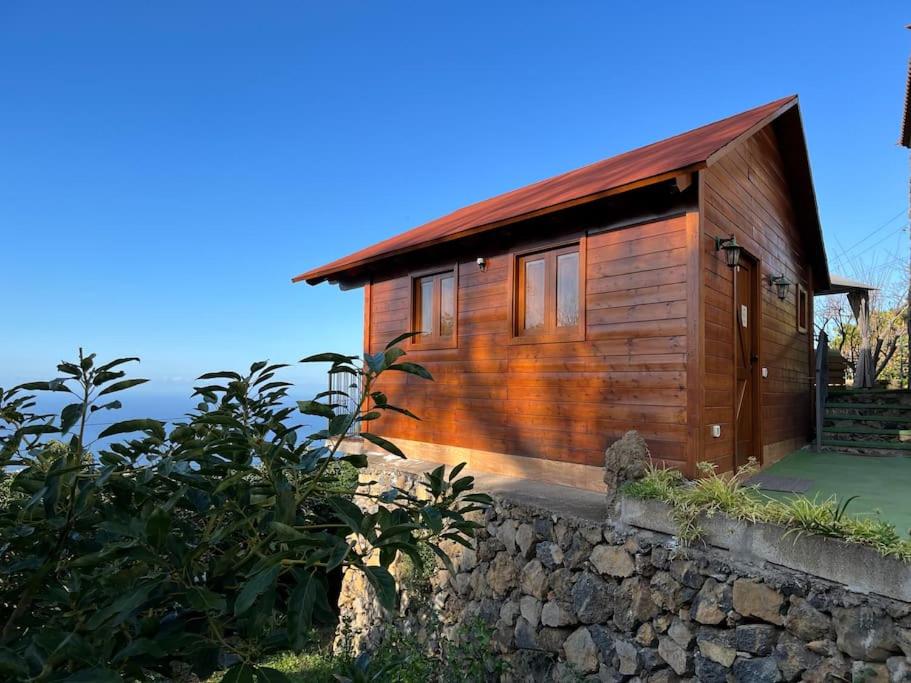 a small wooden cabin with a stone wall at Cozy Mountain Chalet in La Orotava
