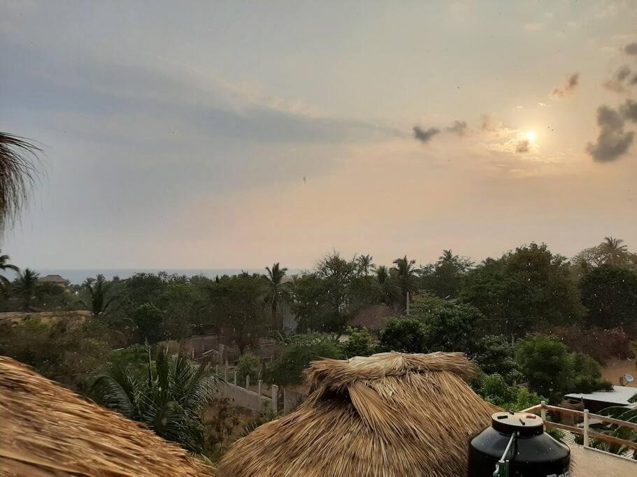a view of a straw roof with a view of a village at La Isla Bonita - Departamento en la Punta in Puerto Escondido