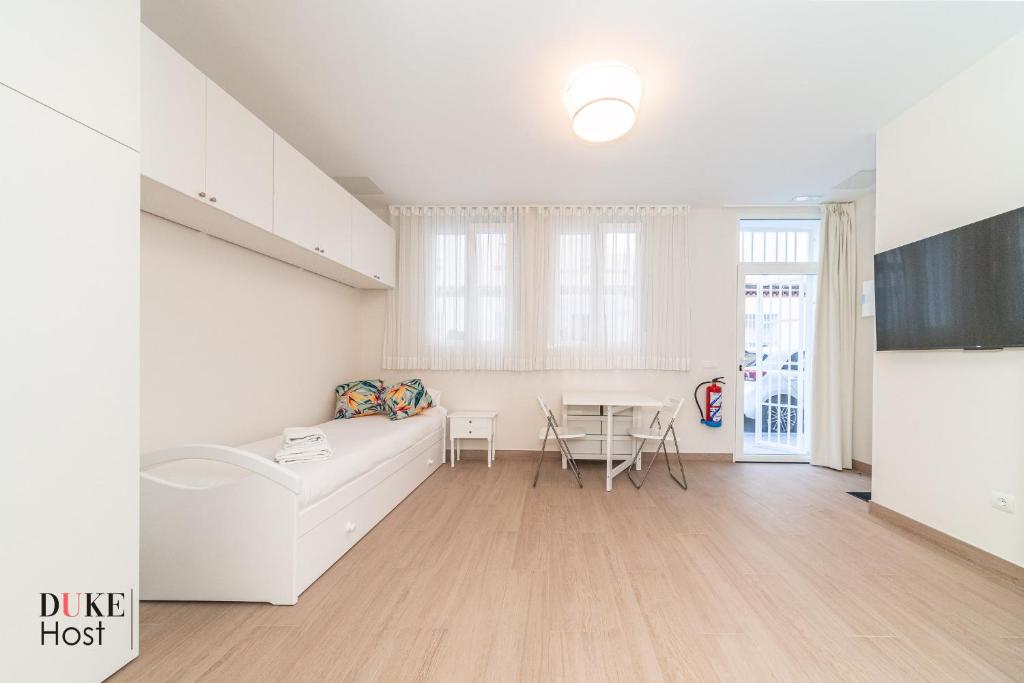 ein weißes Wohnzimmer mit einem Tisch und einem Sofa in der Unterkunft Marqués de Vadillo1 Apartments in Madrid