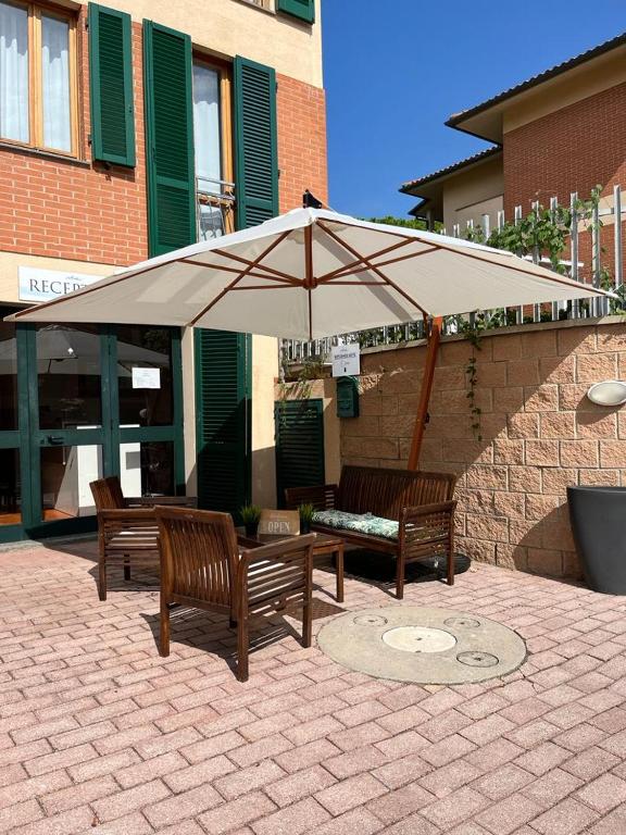 two benches sitting under an umbrella in front of a building at Villaggio Mietta in Castiglioncello