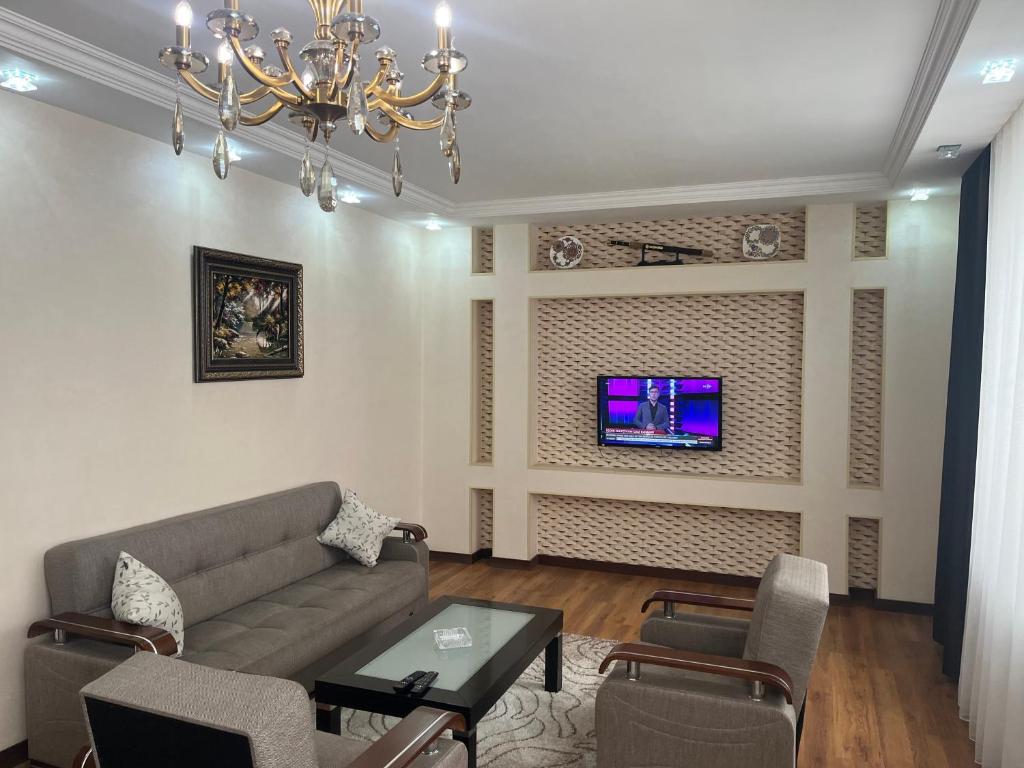 a living room with a couch and a tv on a wall at Beautiful Guest House Qusar in Qusar