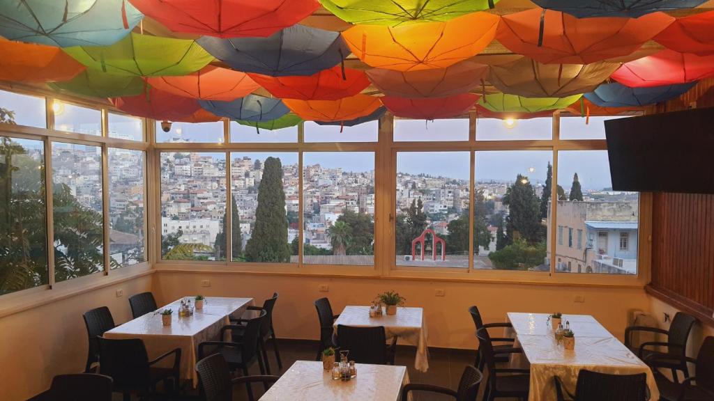 een restaurant met tafels en parasols aan het plafond bij Rosana guest house in Nazareth