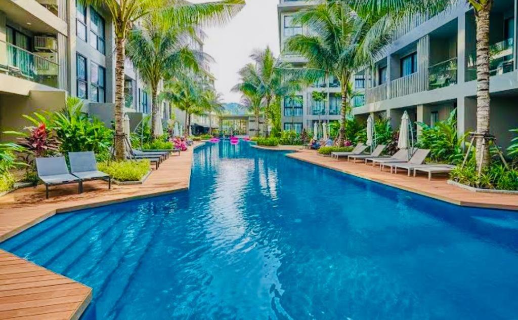 una piscina in un resort con sedie e palme di Diamond Phuket Bang Tao a Bang Tao Beach