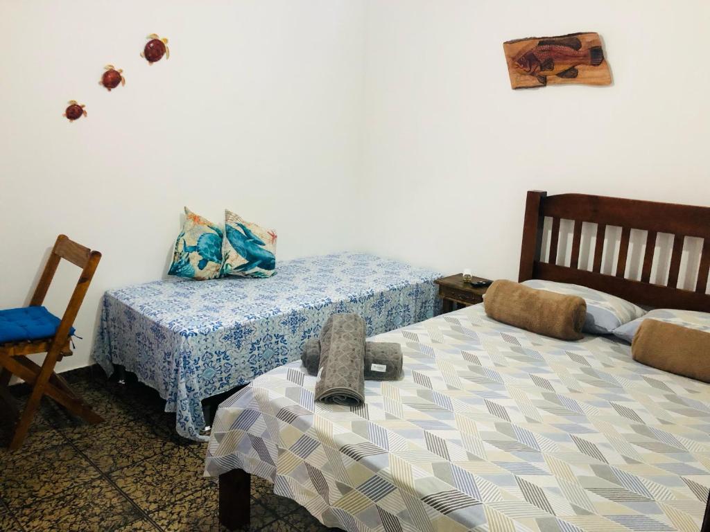 um quarto com 2 camas e uma cadeira em Suíte Trilha do Sol 2 em Arraial do Cabo