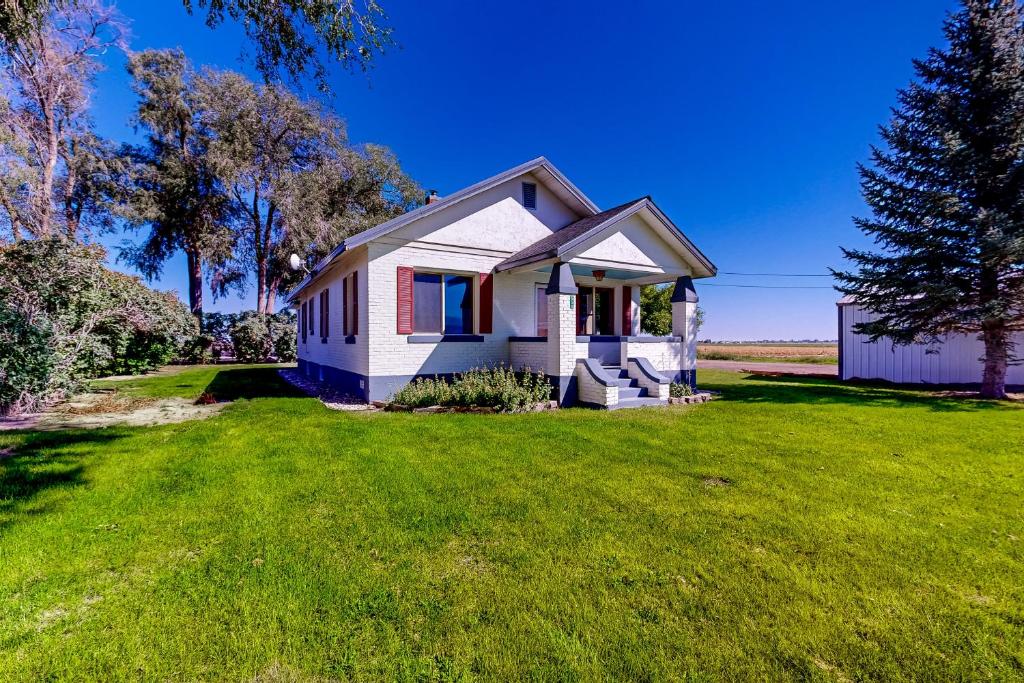 a small white house on a green lawn at The Farmhouse Cottage in Burley