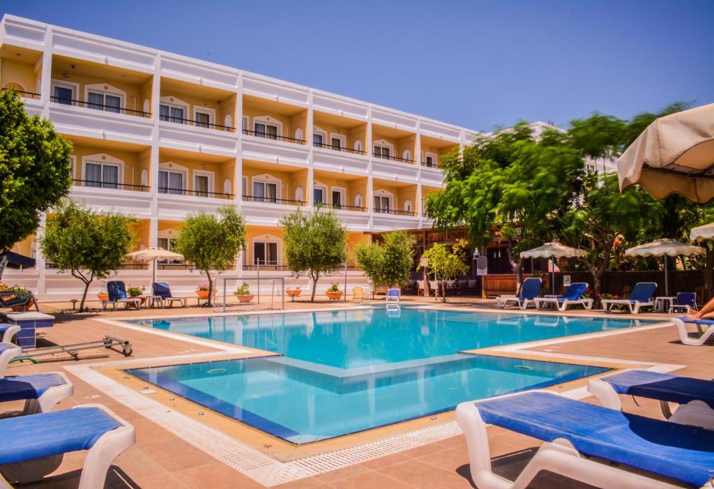 een hotel met een zwembad en stoelen en een gebouw bij Mon Repos Hotel in Faliraki