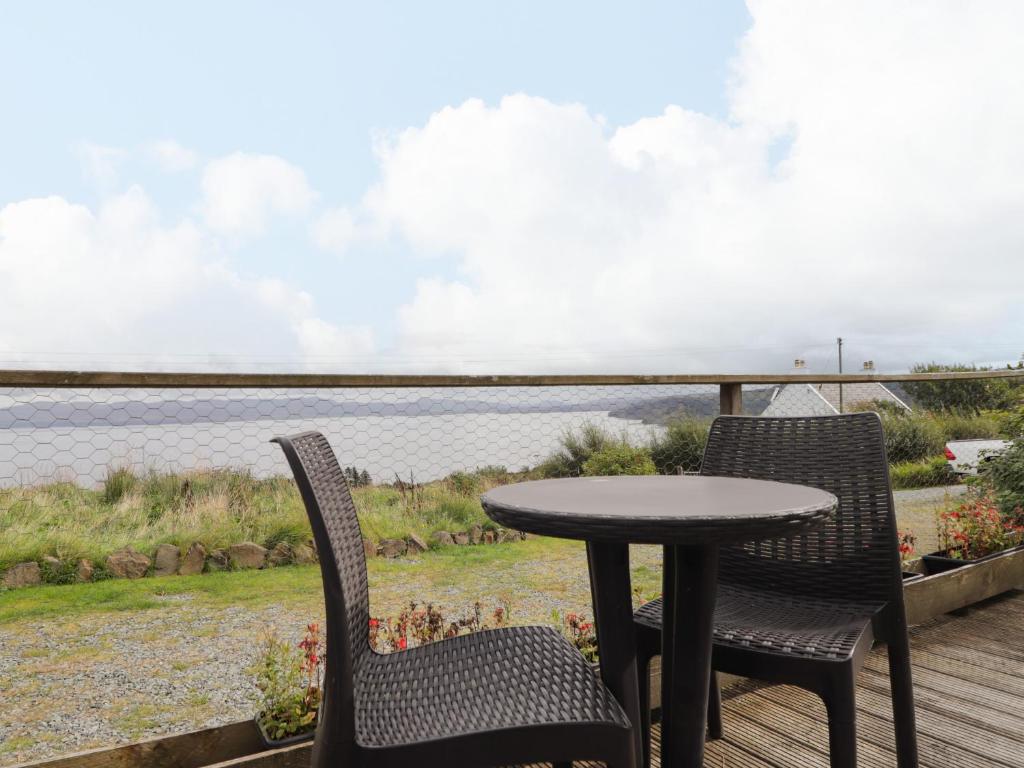 two chairs and a table on a deck with a view of the water at Single Malt Cottage in Geary