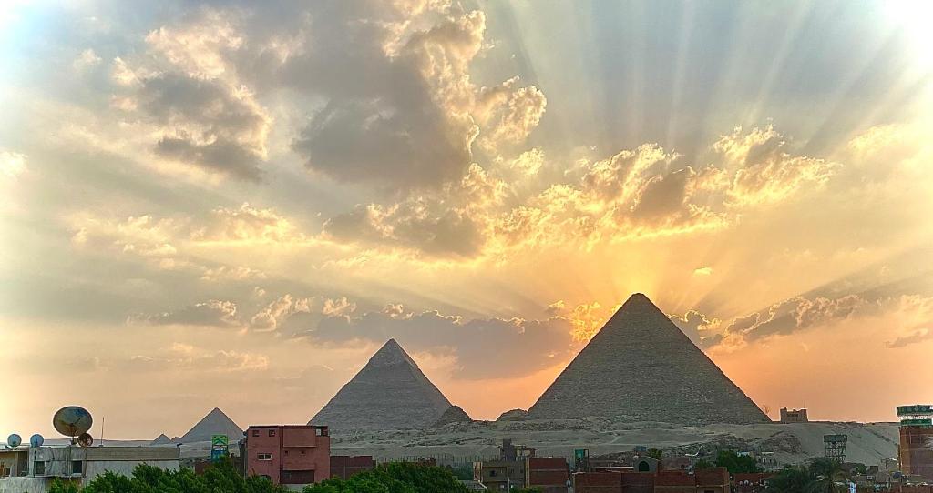 einen Blick auf die Pyramiden von Giza bei Sonnenuntergang in der Unterkunft Pyramids hills view apartment in Kairo