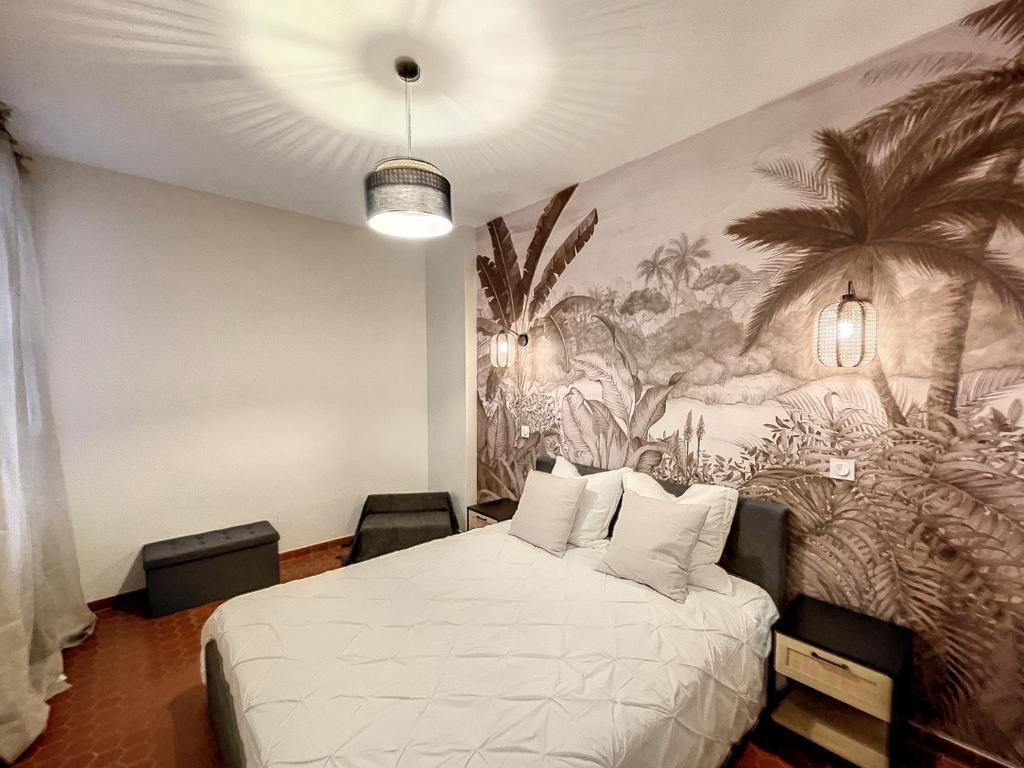 a bedroom with a bed with a mural of palm trees at VIEUX NICE - LE COSY - 5 min des PLAGES - WIFI - PARKING PUBLIC in Nice