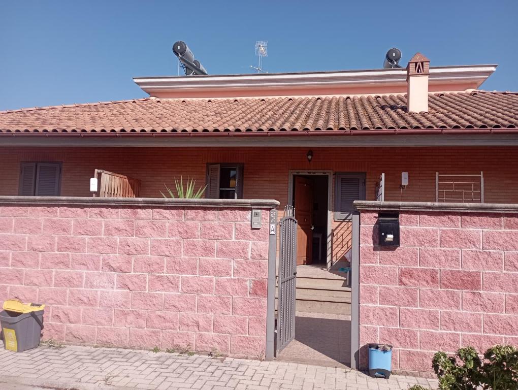 uma casa com uma parede de tijolos cor-de-rosa e um portão em Casa vacanze santa chiara em Marino